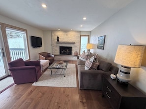 A living room with a fireplace, a sofa, a coffee table, and a television. - Cozy East Vail condo - Mountain view, Hot Tub, Pool & W/D - Near Ski shuttle (Vail)