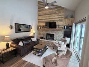Ein Wohnzimmer mit Kamin, Ledersofa, Sesseln und Couchtisch.