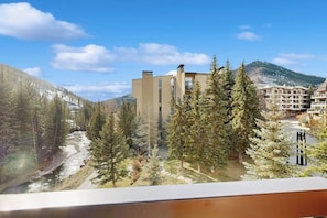 A hotel with a view of a river, trees, and mountains. - Ski-in/out hotel-condo with amazing mountain views, pool, hot tub, & balconies (Vail)