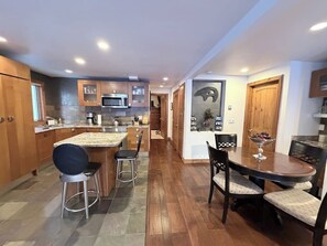 Eine moderne Küche mit Holzausbau, einer Arbeitsplatte aus Granit und einem Essbereich mit Holztisch und Stühlen.
