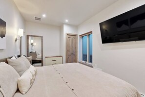Une chambre à coucher avec un lit, une télévision, une armoire, un miroir et une fenêtre.