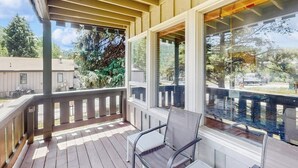 A covered outdoor area with a wooden deck, a glass door, and a chair. - Updated Condo with Walkable Locale, Free WiFi & Private Washer/Dryer (Vail)
