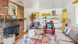 A living room with a brick fireplace, leather sofas, a coffee table, and a patterned rug. - Updated Condo with Walkable Locale, Free WiFi & Private Washer/Dryer (Vail)