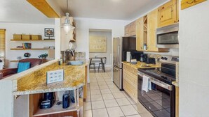 A kitchen with granite countertops, wooden cabinets, a stainless steel refrigerator, and an oven. - Updated Condo with Walkable Locale, Free WiFi & Private Washer/Dryer (Vail)