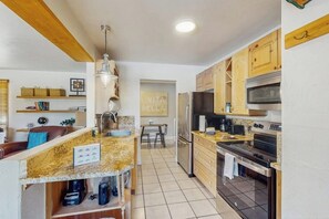 Eine Küche mit Granit Arbeitsplatten, Holzschränken, einem Edelstahlkühlschrank und einem Backofen.