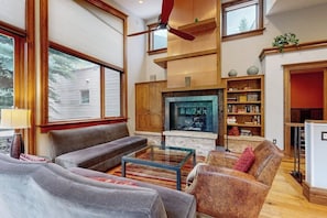 Ein modernes Wohnzimmer mit Kamin, Deckenventilator und Bücherregal.