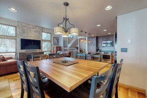 A modern kitchen with a central island, built-in appliances, and a dining area with a wooden table and chairs. - Townhome w/ Gorgeous View, Gas Fireplace & Fast WiFi - Steps to Ski Shuttle (Vail)