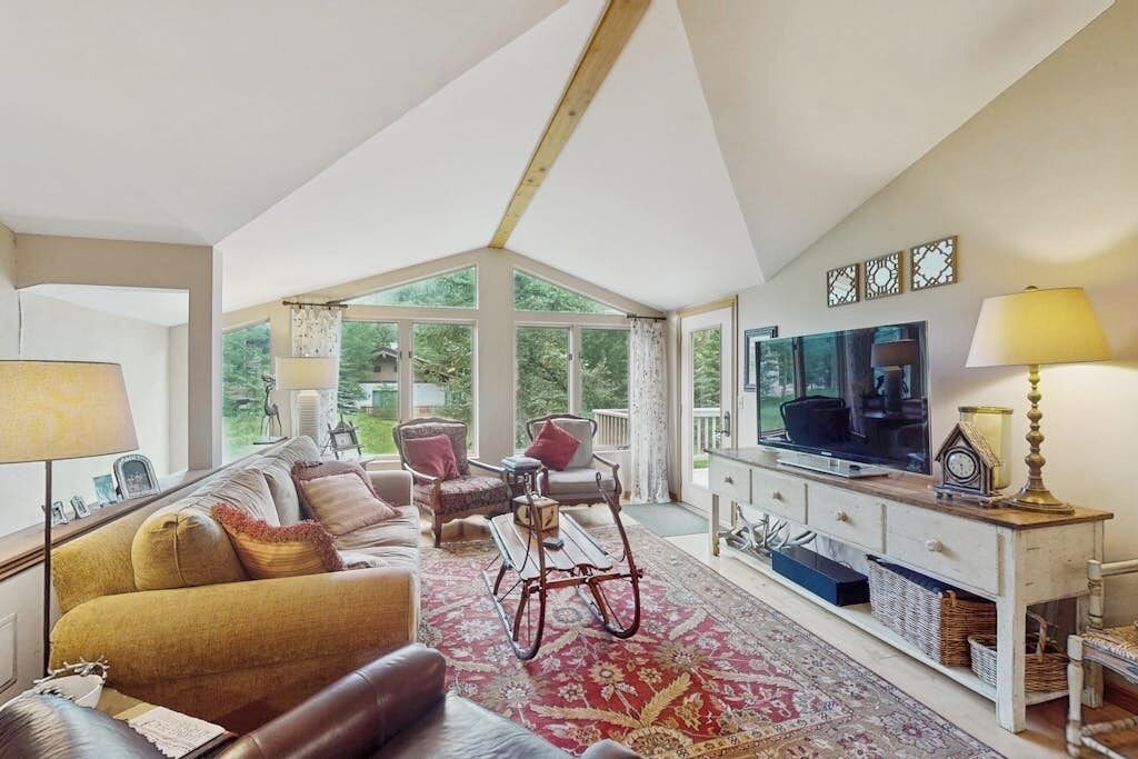 A spacious living room with a sofa, chairs, a television, and a large window.
