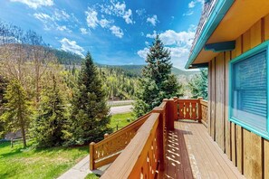 Ein hölzerner Balkon mit Blick auf ein bewaldetes Tal und eine Straße.