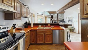 A kitchen with wooden cabinets, a stove, a sink, and a dishwasher. - Quiet, multi-level townhome with great location & mountain views (Vail)