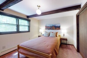 A bedroom with a bed, two bedside tables, a window, and a wall-mounted picture. - Quiet mountain-view condo with patio, fireplace & grill - walk to Vail bus (Vail)