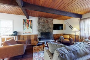 A cozy living room with a stone fireplace, wooden beams, and comfortable seating. - Quiet mountain-view condo with patio, fireplace & grill - walk to Vail bus (Vail)