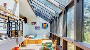 A sunlit room with a pool table, chairs, and large windows. - Mountain-view home with private hot tub, solarium & fireplace - steps to shuttle (Vail)