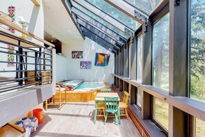 A sunlit room with a pool table, chairs, and large windows. - Mountain-view home with private hot tub, solarium & fireplace - steps to shuttle (Vail)