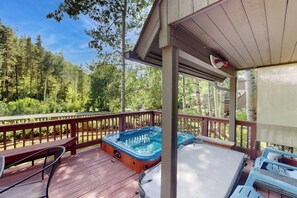A hot tub on a wooden deck with a view of a forest. - Charming home with private hot tub, fireplace, washer/dryer, and central AC (Vail)