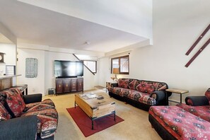 Ein Wohnzimmer mit Sofa, Couchtisch, Fernseher und Schrank.