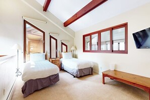 Ein Schlafzimmer mit zwei Betten, einer Bank, einem Fernseher und einem großen Fenster.