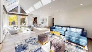 A spacious living room with a blue leather sofa, a white bean bag chair, and a patterned rug. - Three-story townhouse with balcony, mountain views, fireplace, grill, & W/D (Vail)