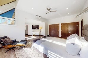 A modern bedroom with a large bed, a ceiling fan, and a view of the outdoors. - Three-story townhouse with balcony, mountain views, fireplace, grill, & W/D (Vail)