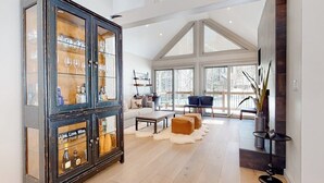 Een ruime woonkamer met een grote kast, een bank, een salontafel en uitzicht door grote ramen.