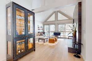 Ein großzügiger Wohnbereich mit einem großen Schrank, einer Couch, einem Couchtisch und Blick durch große Fenster.