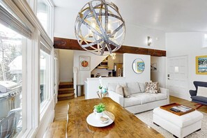 A modern living room with a wooden coffee table, a white sofa, and a unique spherical chandelier. - Cozy Condo walk to Lionshead, On Bus Route (Vail)