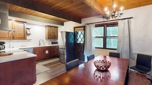 A kitchen with wooden cabinets, a dining table with chairs, and a chandelier. - Remodeled, mountain view townhome with patio, fireplace & great location (Vail)