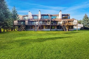 A multi-story house with a large lawn, multiple balconies, and a staircase leading to the upper levels.