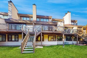 Kerrostalo, jossa on useita kerroksia, keskeinen portaikko, parvekkeet ja hyvin hoidettu nurmikko.