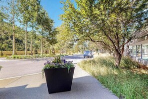 A paved road with a black planter box with flowers, trees, and a building with large windows. - Rustic condo with resort amenities, sweeping views, and wood-burning fireplace (Vail)