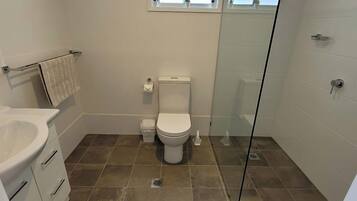 A bathroom with a toilet, sink, and shower area.