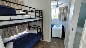 A room with a bunk bed, a small table with a towel, and a bathroom visible through an open door. - Morton A - Cabin with Views and Deck (Mollymook)