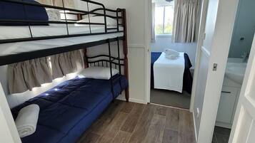 A room with a bunk bed, a small table with a towel, and a bathroom visible through an open door.
