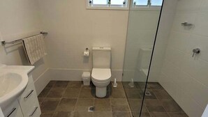 Une salle de bain comprenant des toilettes, un lavabo et un espace douche.