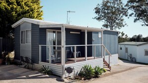 Une petite maison mobile d’un seul étage, dotée d’un porche, d’une porte coulissante et d’une petite terrasse.