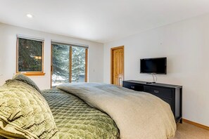 Ein Schlafzimmer mit Bett, Fernseher, Kommode und einer Glastür.
