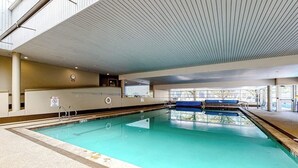 An indoor swimming pool with clear water, a tiled floor, and a ceiling with linear patterns. - Charming condo with resort amenities, sweeping views, & wood-burning fireplace (Vail)