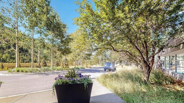 A paved pathway lined with trees and a planter with flowers. - Charming condo with resort amenities, sweeping views, & wood-burning fireplace (Vail)