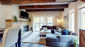 Una sala de estar con chimenea, un sofá, un televisor y un comedor con una silla.