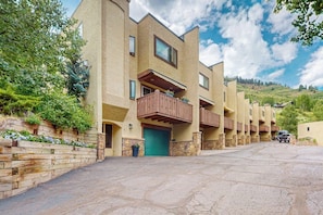 A multi-story building with balconies, a stone facade, and a green door. - Charming townhouse with private hot tub, mountain views, and family-friendly (Vail)