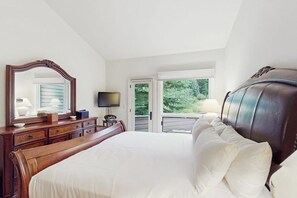 A bedroom with a large bed, a dresser, a television, and a window with a view of greenery. - Comfortable home with fully stocked kitchen & W/D - great location (Vail)