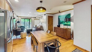 Una cocina moderna con una mesa de comedor de madera, electrodomésticos integrados y un amplio ventanal.