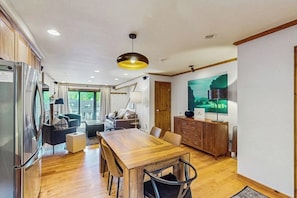 A modern kitchen with a wooden dining table, built-in appliances, and a large window. - Conveniently located condo w/ full kitchen, W/D & balcony with great views (Vail)