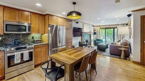 Una cocina moderna con armarios de madera, electrodomésticos de acero inoxidable y un comedor con mesa y sillas de madera.