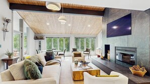 A spacious living room with a high ceiling, large windows, a fireplace, and modern furniture. - Luxurious Vail Home with private hot tub, patio, fireplace, and bus to slope (Vail)