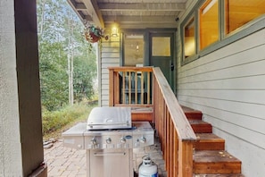 Ein Grill auf einer Veranda, mit Treppen, die zu einer Tür führen.