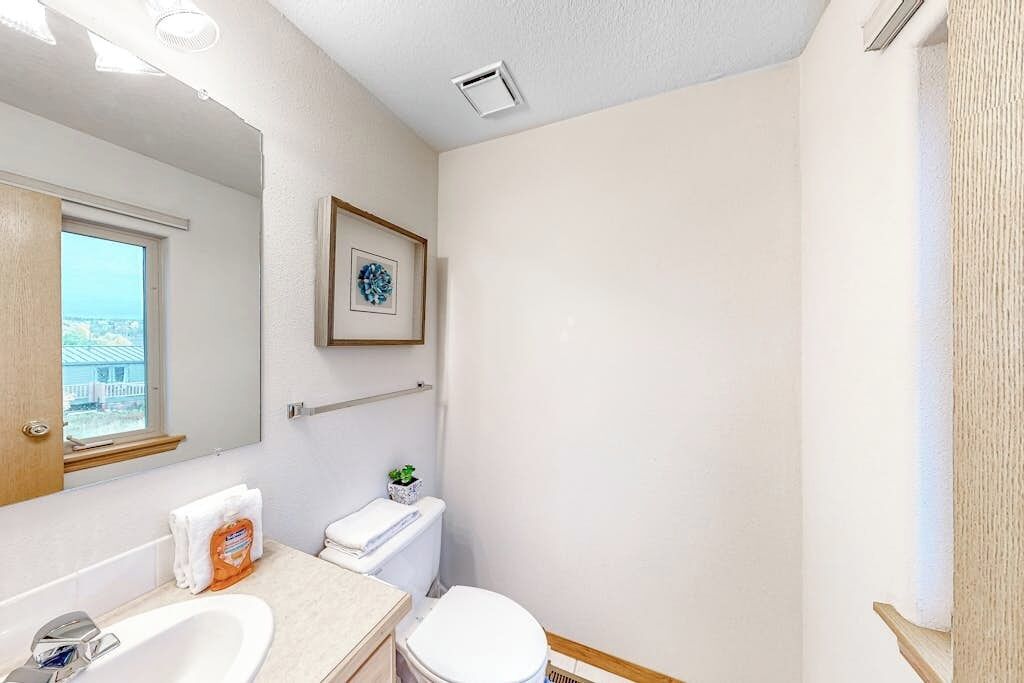 A bathroom with a sink, toilet, and a framed picture on the wall.