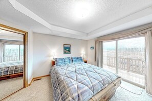 Ein Schlafzimmer mit einem Bett, einem großen Fenster, einem Spiegel und einem Gemälde an der Wand.