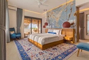 Ein modernes Schlafzimmer mit einem großen Bett, einem blauen Sessel, einem Holzkopfende und einem gemusterten Teppich.