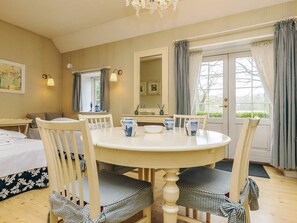 A room with a round table, four chairs, a bed, a mirror, and a window with curtains. - 4 Person Holiday Home in Faaborg (Faaborg)